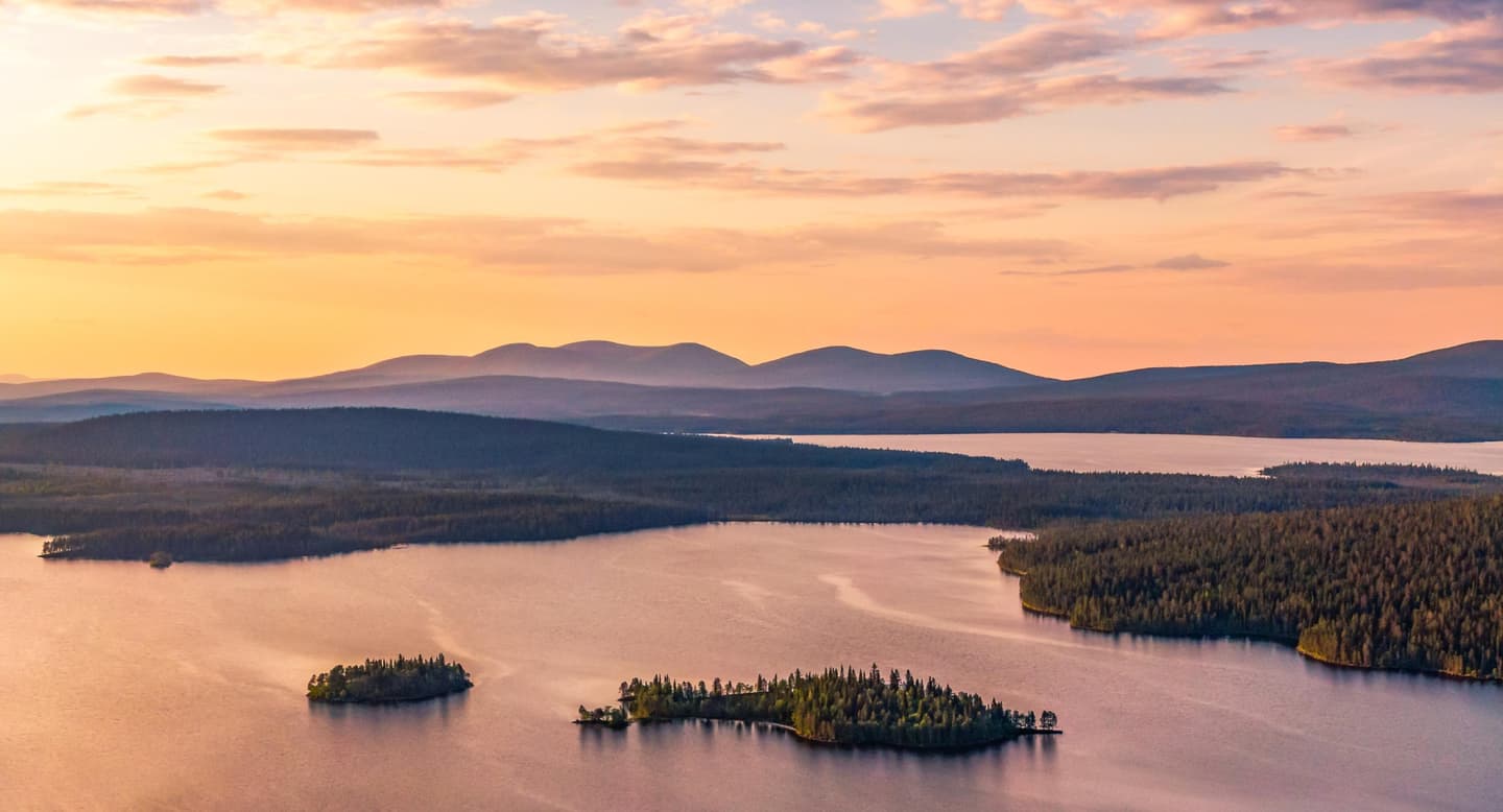 Image: Rami Valonen A lake with islands in the evening glow. Fells rise in the background.