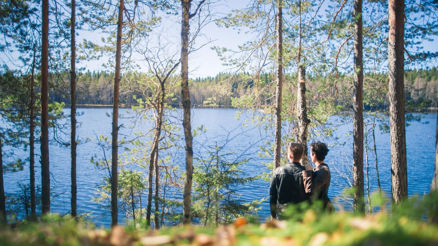Image: Laura Vanzo / VisitTampere Kaksi ihmistä seTwo people stand near to each other close to the shore, looking at the lake on a summer day.isoo lähekkäin rannan tuntumassa katsellen järvelle kesäpäivänä.