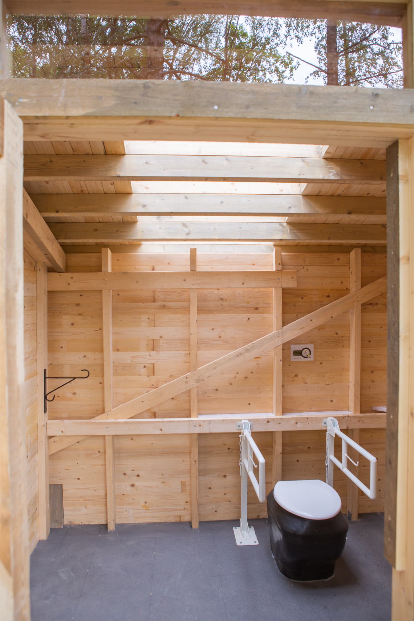 Kuva: Joel Heino Esteetön wc-istuin käymälän sisällä. Seinät ovat vaaleaa puuta ja katosta tulee ikkunan läpi valoa.