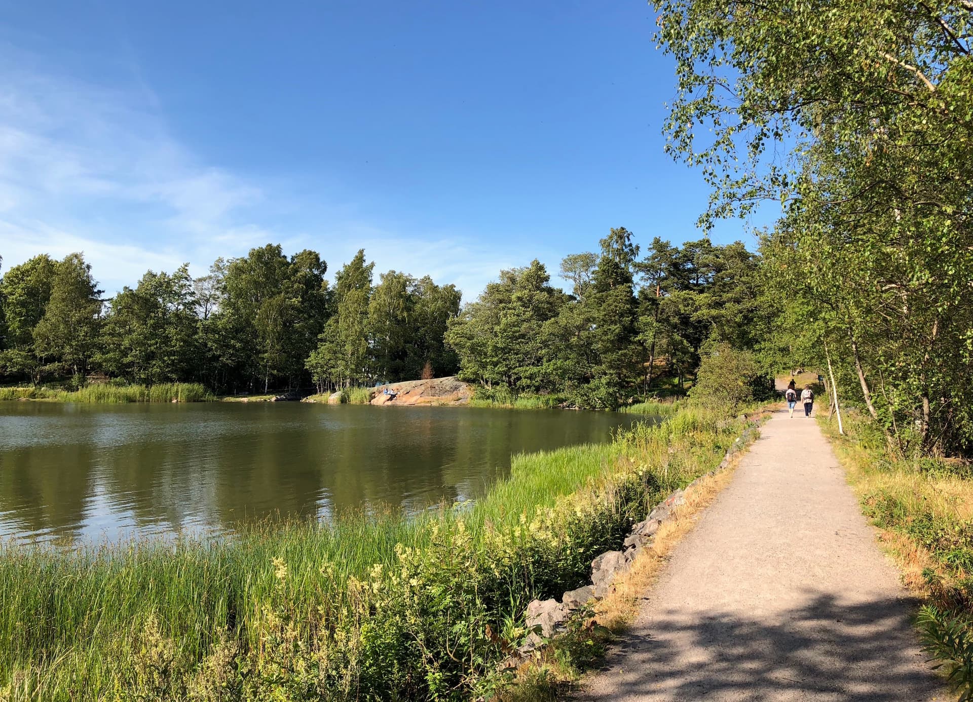 Kuva: 110th Street Productions / Helsingin kaupunki Ihmisiä kävelemässä rantatiellä aurinkoisena kesäpäivänä.