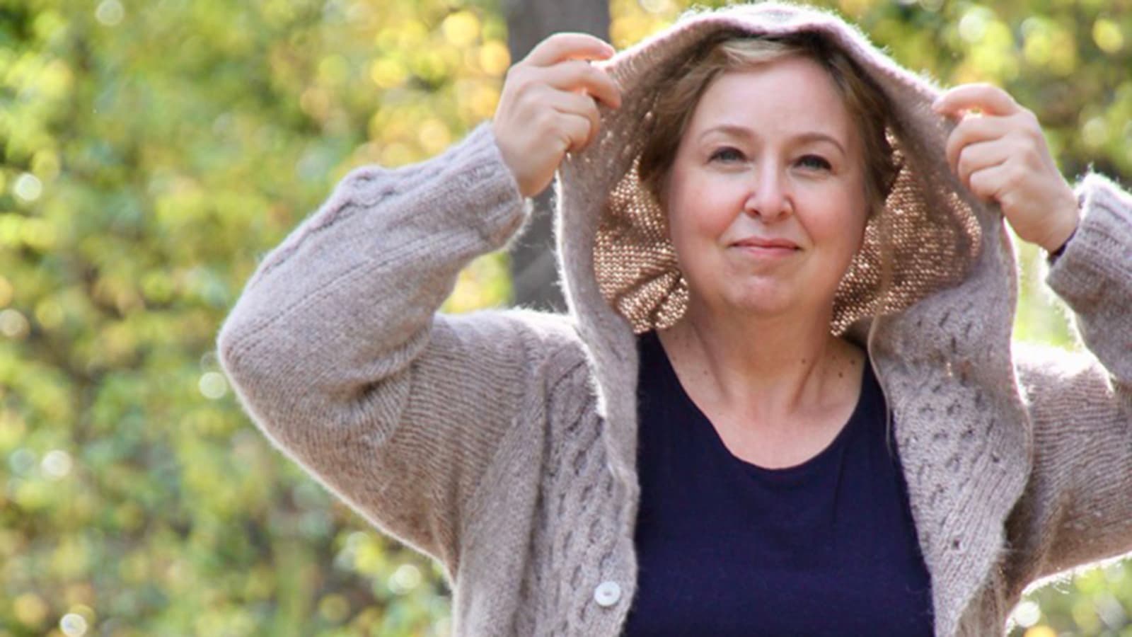 Image: Sanna Piiroinen A person is pulling up the hood of a grey wool cardigan on a summer’s day.