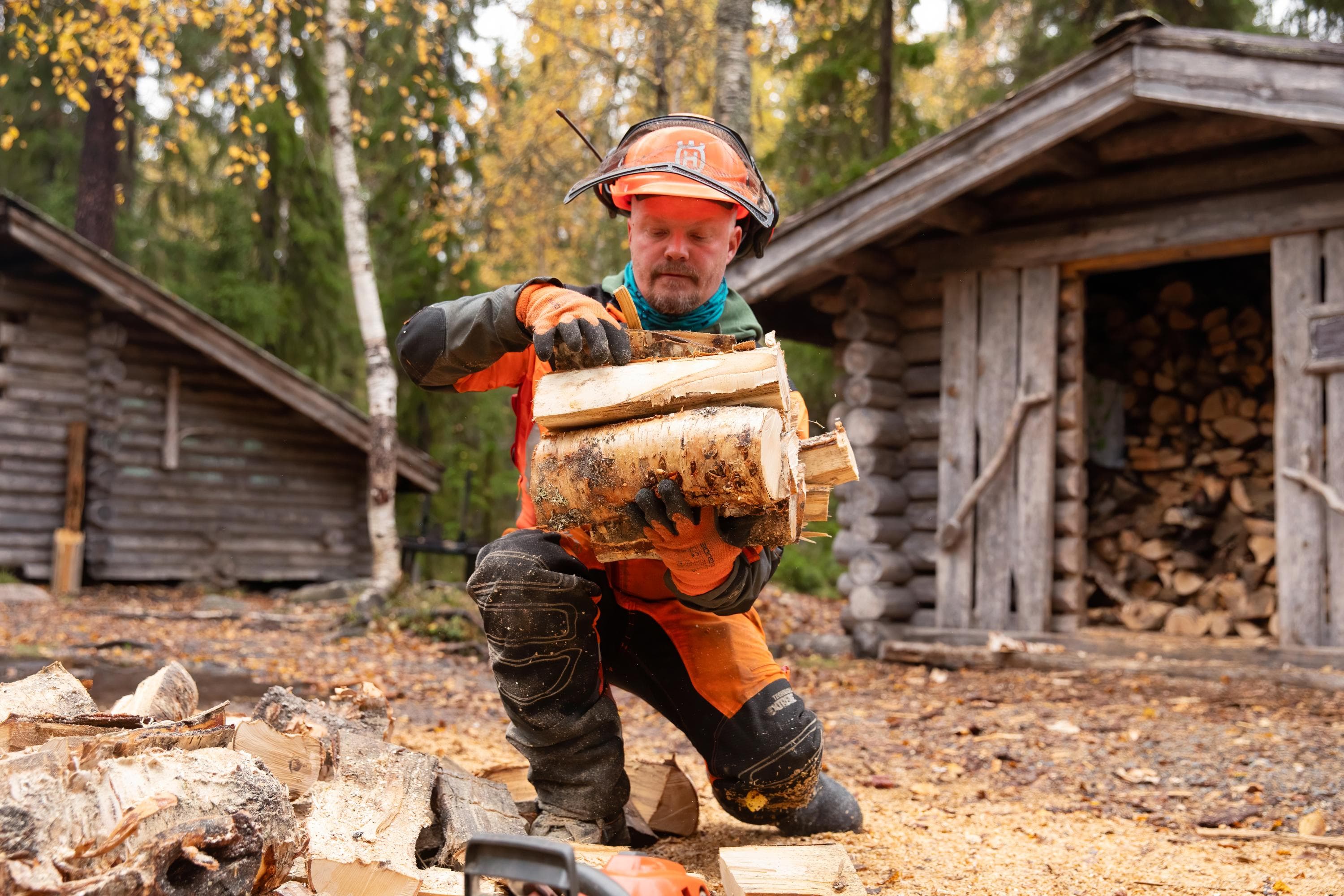 Kuva: Kuvatoimisto Keksi, Katri Lehtola. Mies kasaa polttopuita syliinsä taukopaikalla.