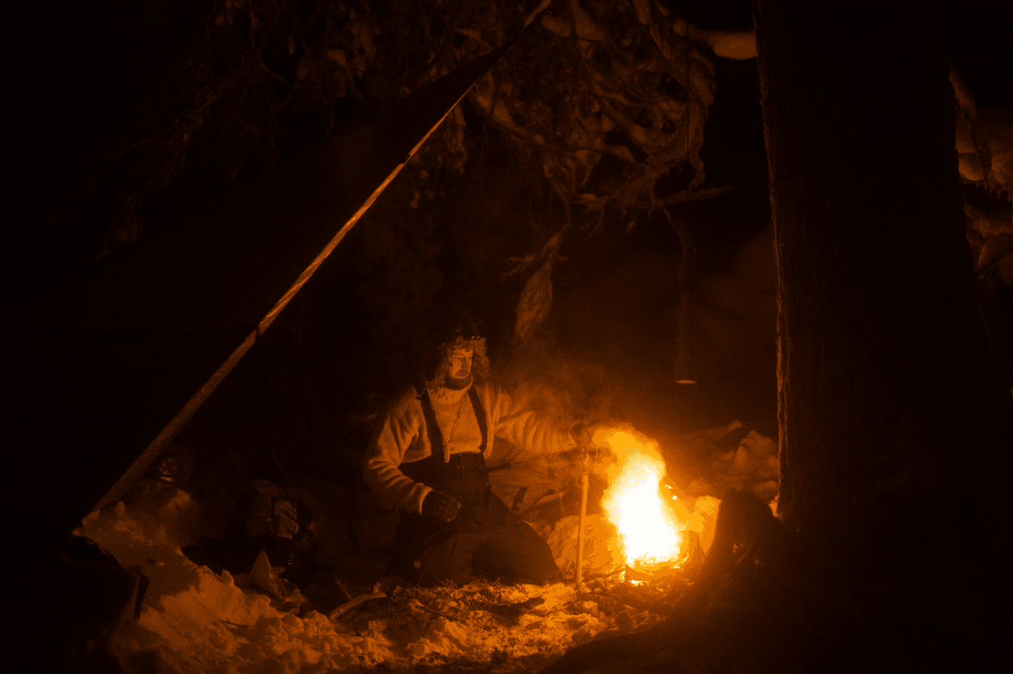 Image: Sakari Raappana A person sitting by a campfire in the dark during winter.
