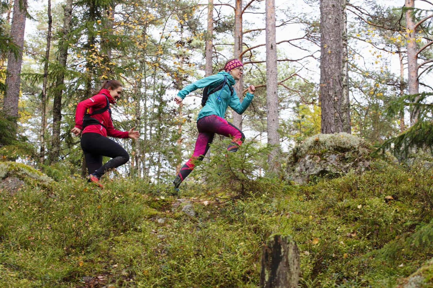 Image: Katri Lehtola Two people are running on a forest path. Both are wearing colorful clothes.