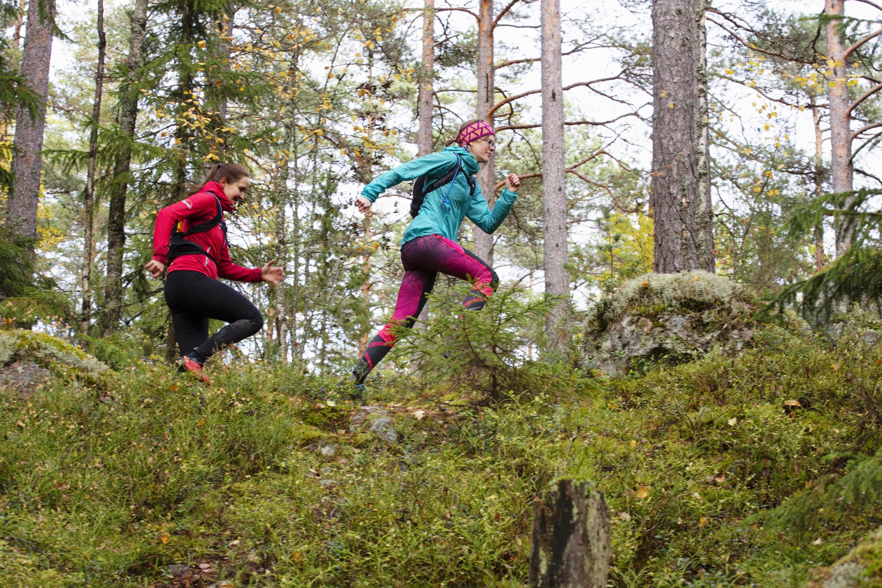 Bild: Katri Lehtola Två personer springer på en skogsstig. Båda har färgglada kläder.