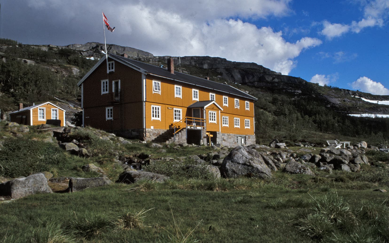 Kuva: Tage Lampen Norjalainen palvelutupa kivikoisessa maisemassa puolipilvistä taivasta vasten.