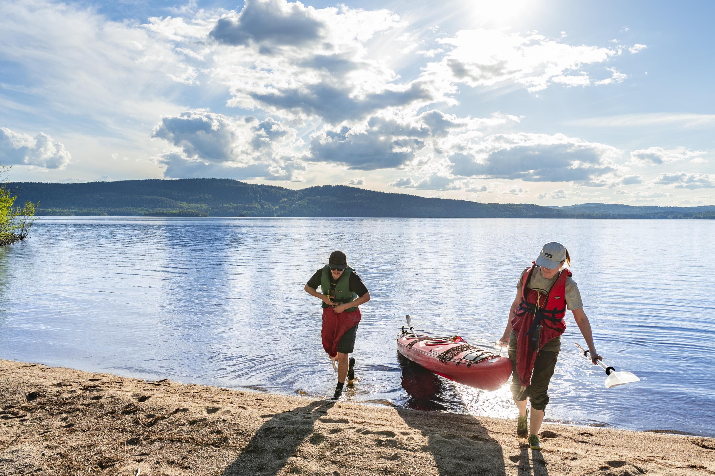 Bild: Samuli Kuittinen Två vandrare och en kayak på stranden.