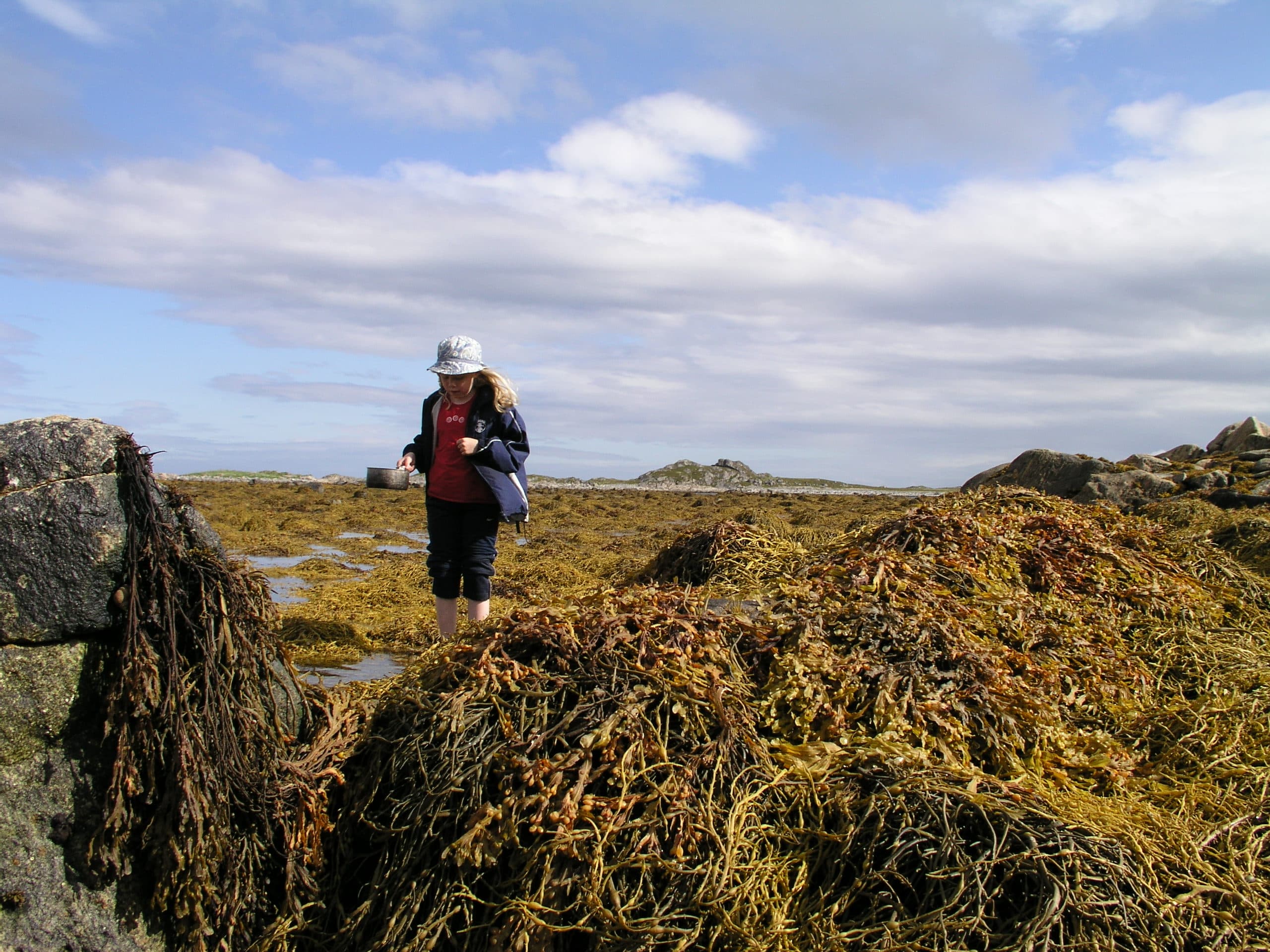 Kuva: Ari Karhilahti Lapsi vuonon rannalla trangian kattilan kädessä.