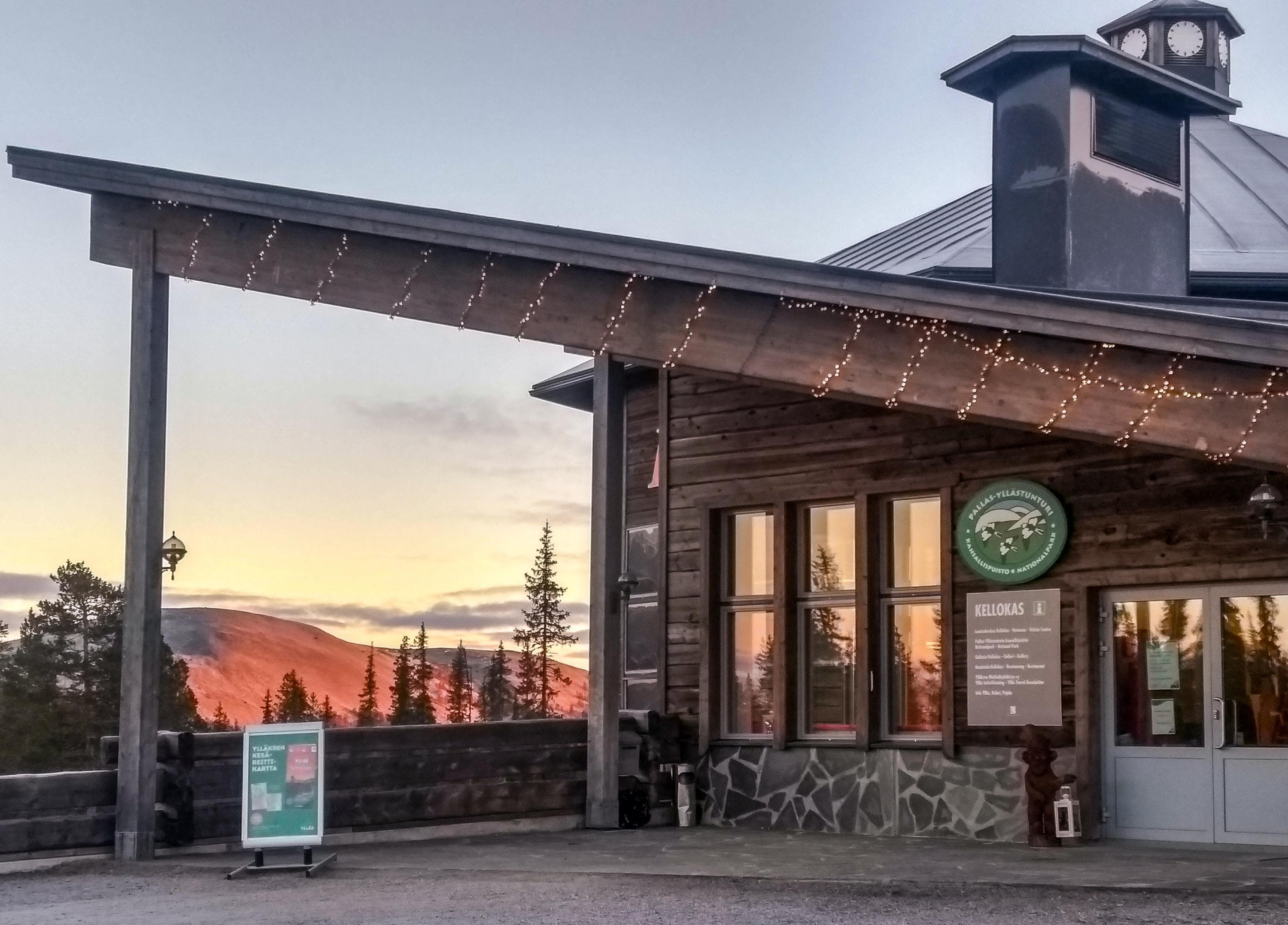Hirsisen rakennuksen sisäänkäynti. Rakennuksen takana näkyy tunturimaisemaa.