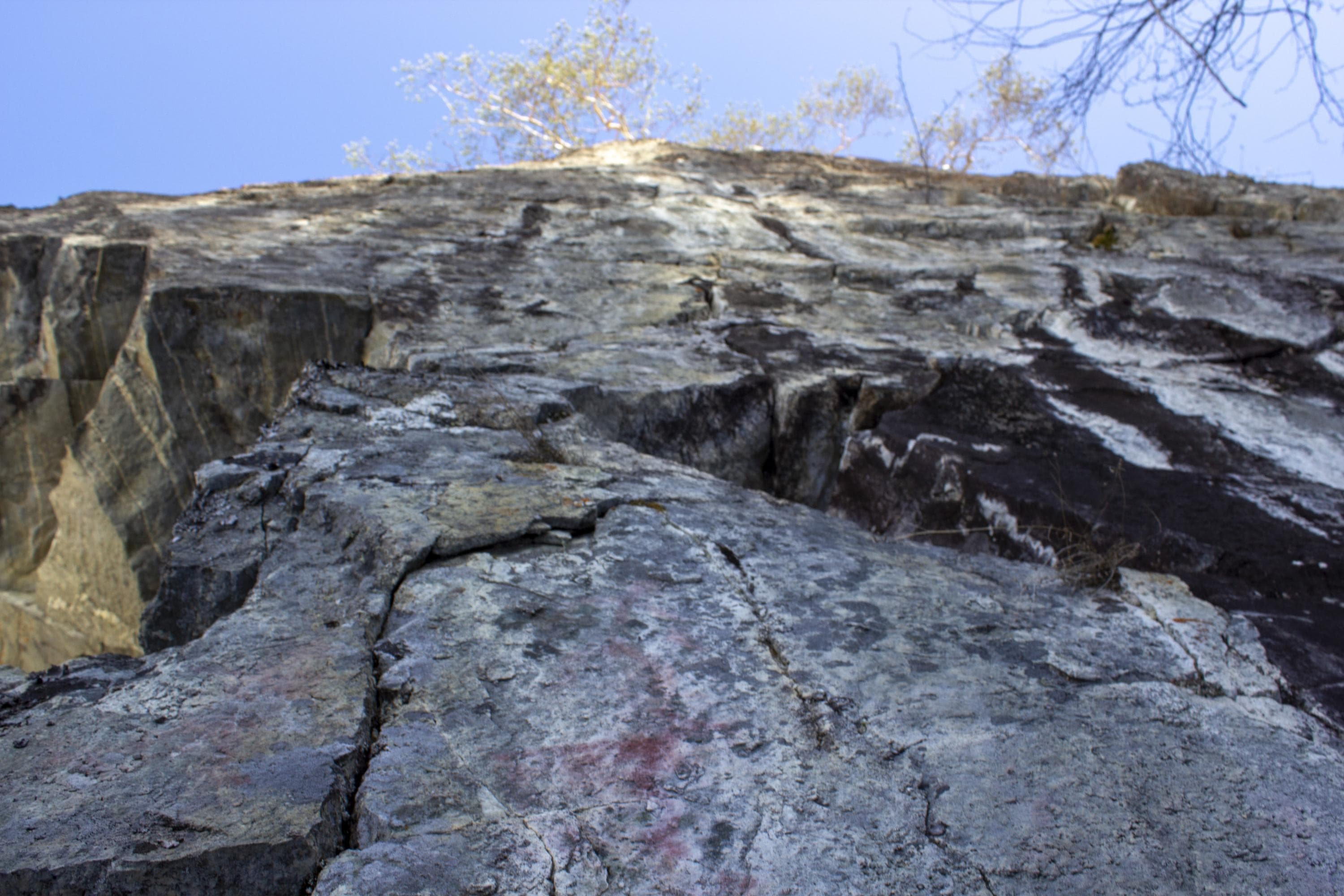 Kuva: Sirke Seppänen Alhaalla kolme kalliomaalauskuviota, yllä poutataivas.