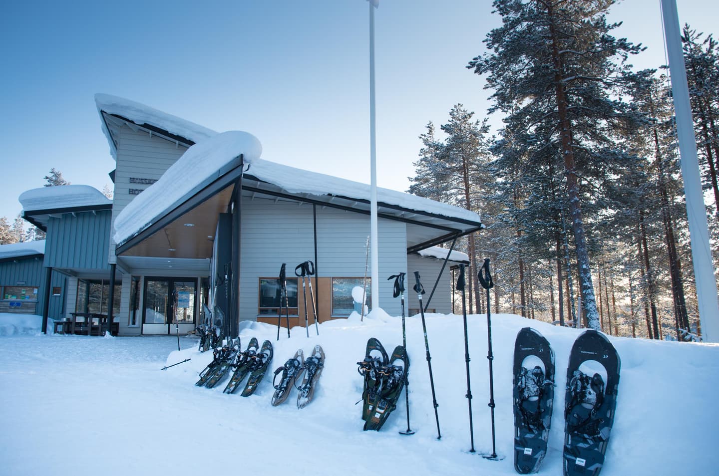 Kuva: Tuuli Turunen Luontokeskusrakennus talvella. Rakennuksen edessä on lumikenkiä pystyssä lumihangessa.