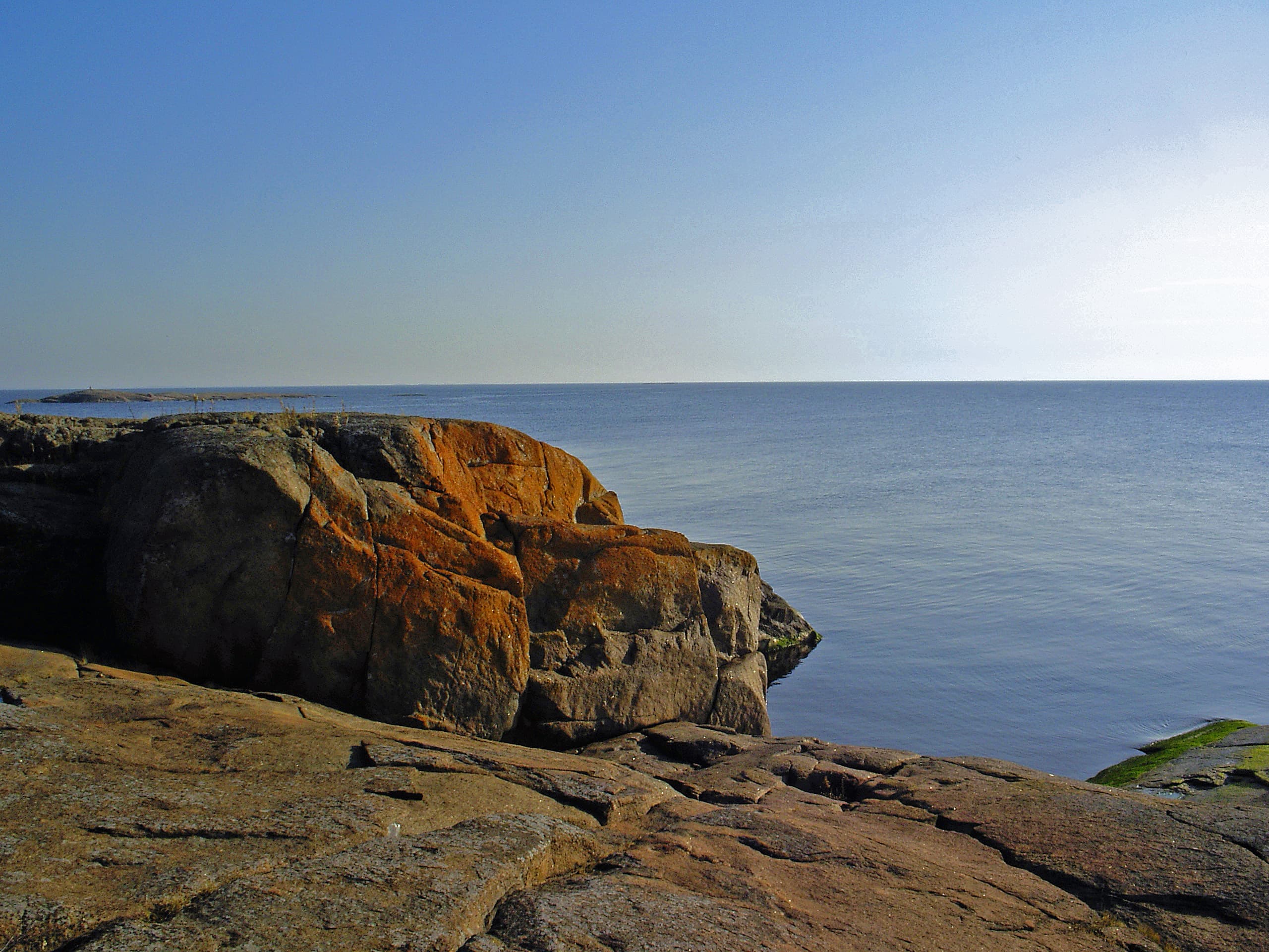 Kuva: Essi Keskinen Kallioinen ranta ja lähes tyyni merimaisema. Pilvetön taivas.