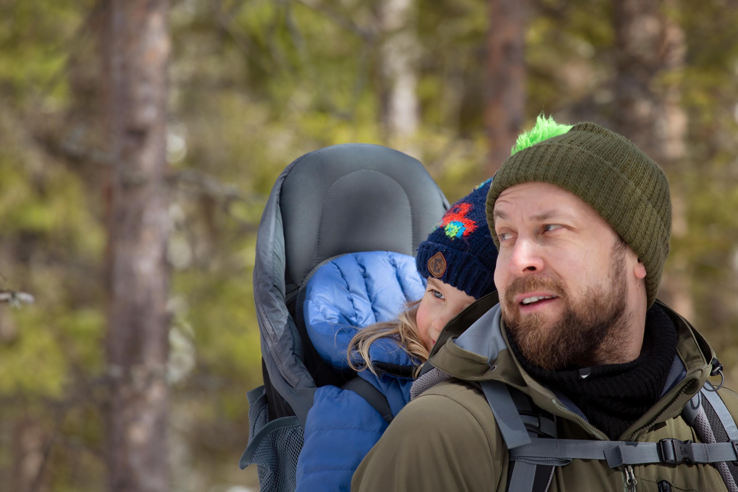 Kuva: Katri Lehtola / Keksi Lapsi nojaa isän selkään kantorepussa. Aikuinen kurkkaa olan yli lasta kohti. Taustalla epätarkka metsä.