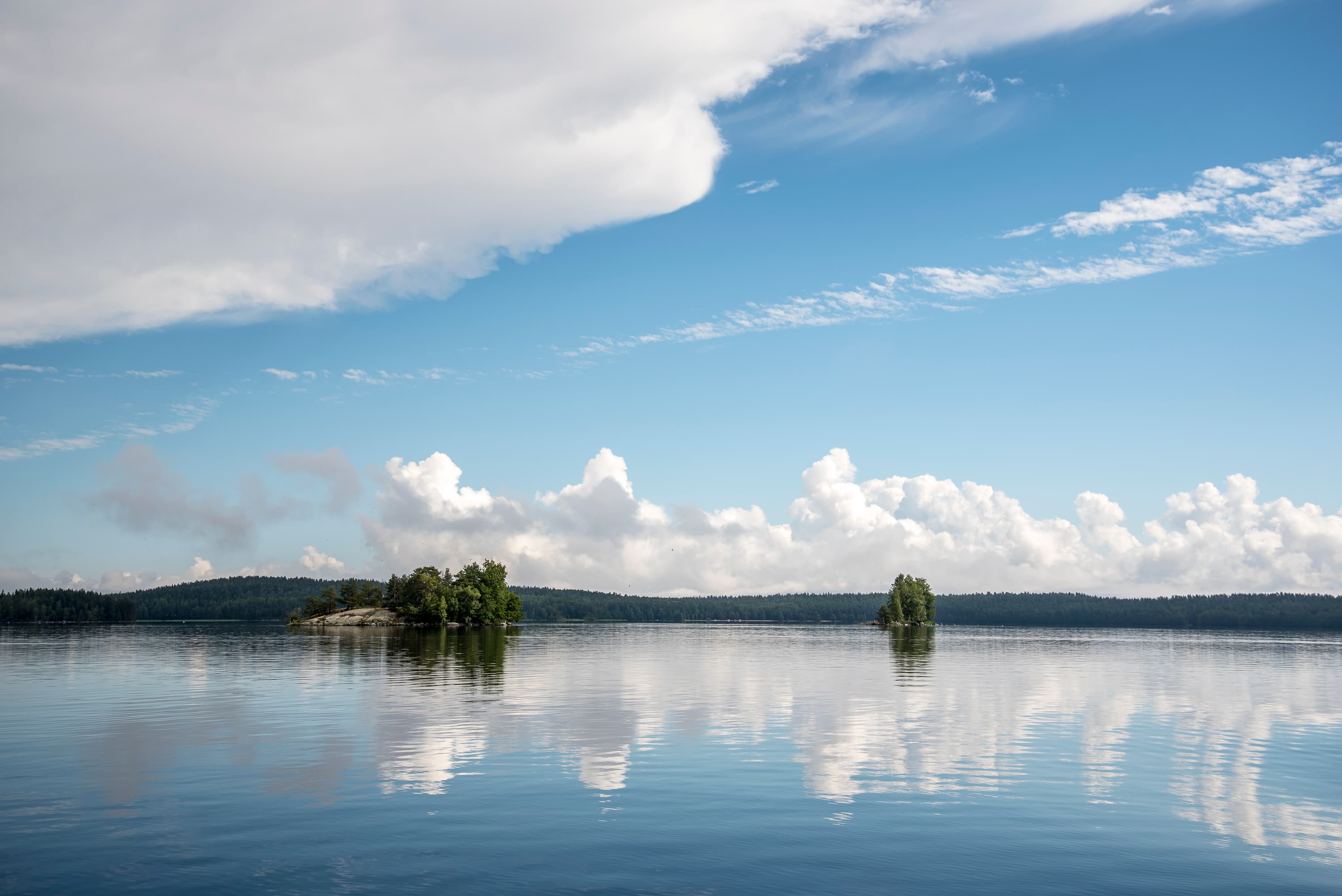 Kuva: Jari Ilmonen Peilityyni järvi, jossa on saaria ja pilvet heijastuvat veden pintaan.