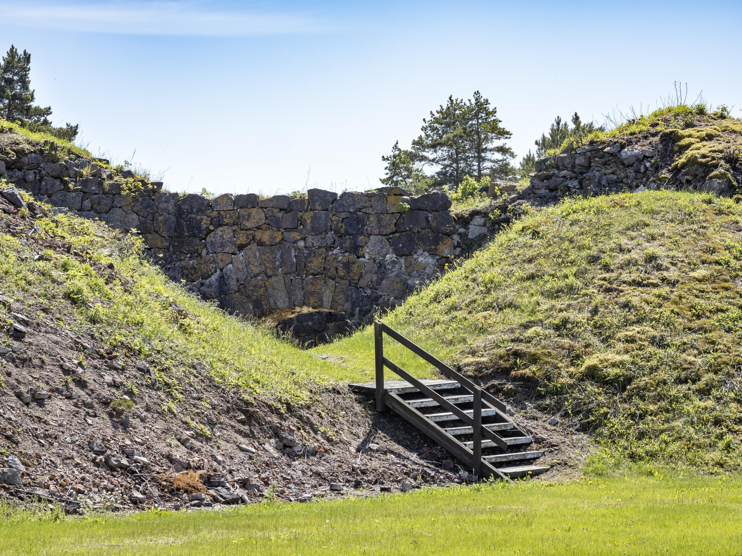 Kuva: Jari Kostet Lyhyet portaat johtavat kahden kumpareen väliin. Taustalla linnoituksen rakennelmia.