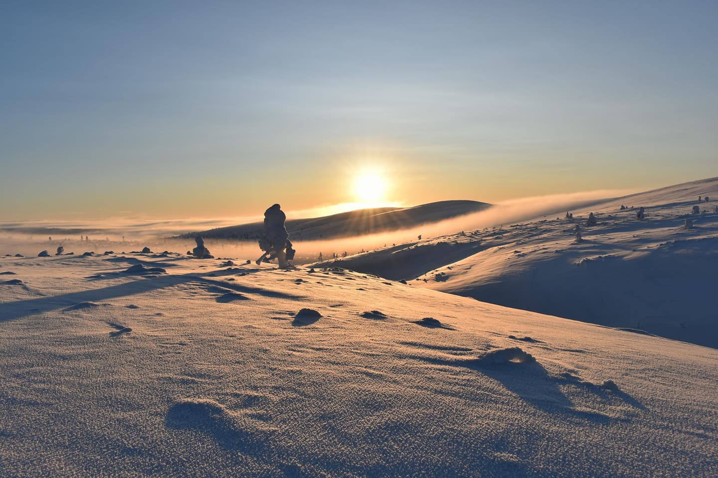 Image: Tero Turpeinen The sun shines from behind the snowy fell. On the slopes of the fells, there are only a few snow-covered pines.