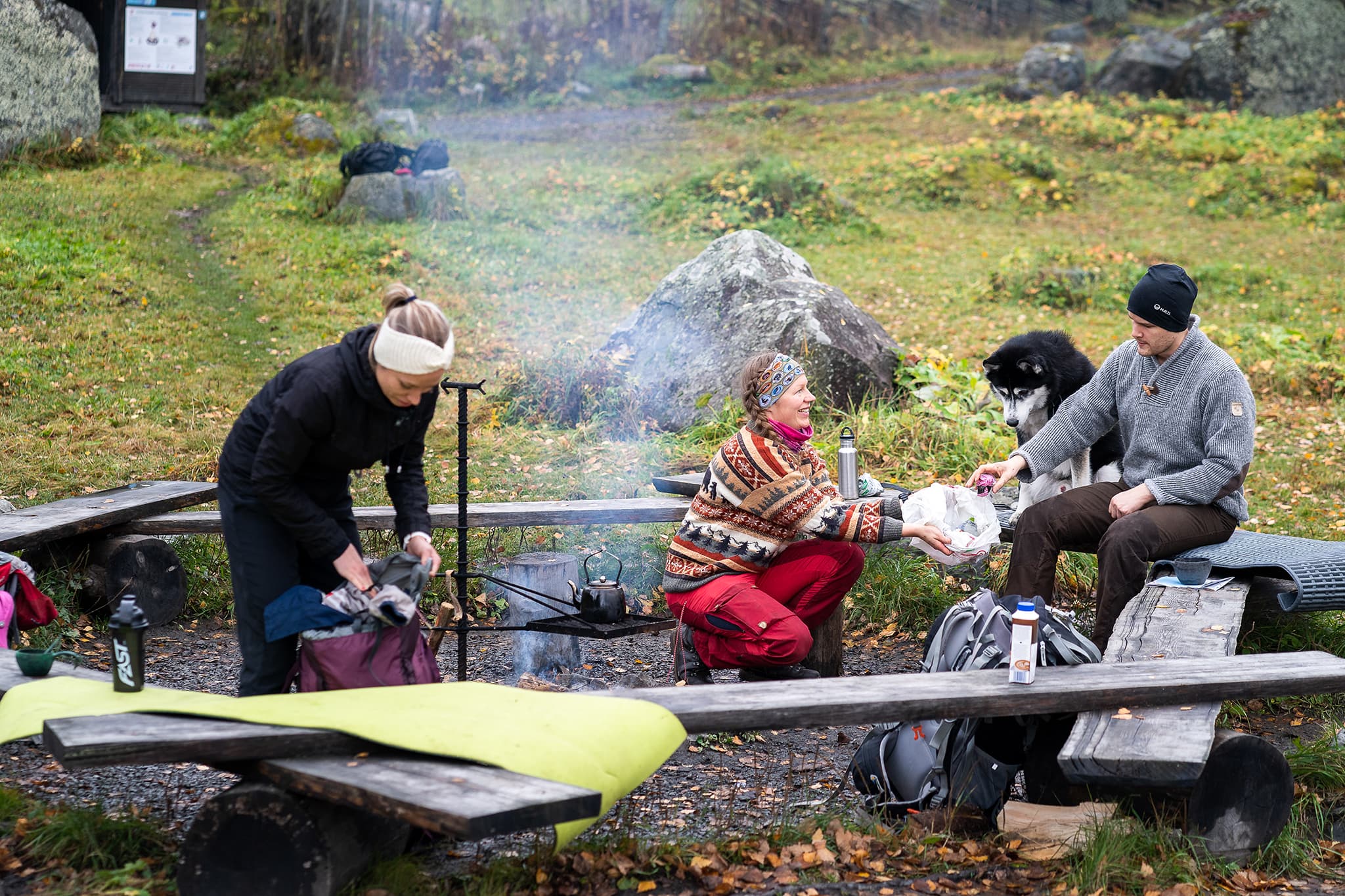 Kuva: Mitja Piipponen Kolme retkeilijää tulentekopaikalla. Yksi kokoaa roskia pussiin.