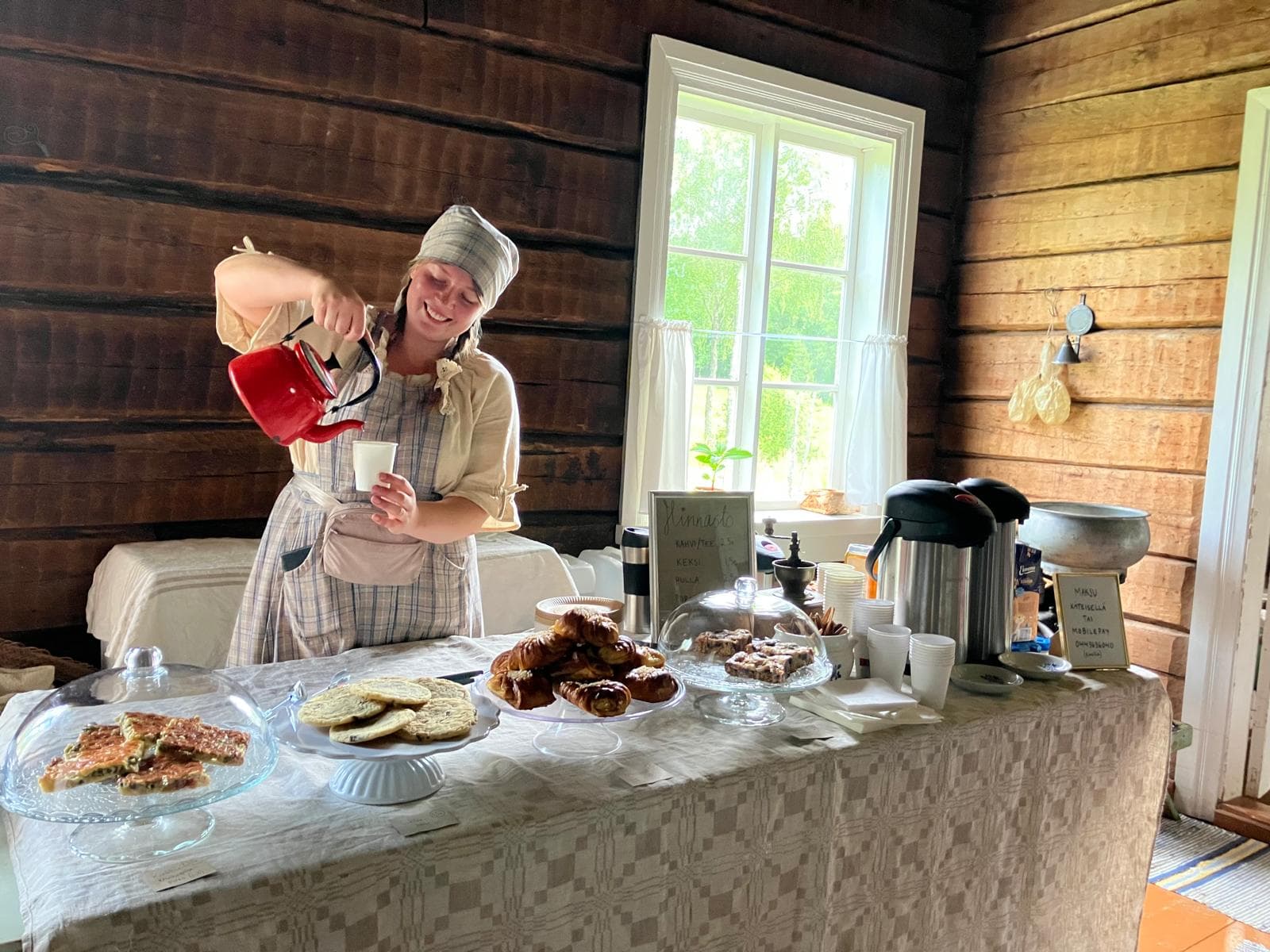 Kuva: Emilia Niemi Henkilö kaataa kahvipannusta kahvia. Pöydällä on tarjolla erilaisia leivonnaisia.