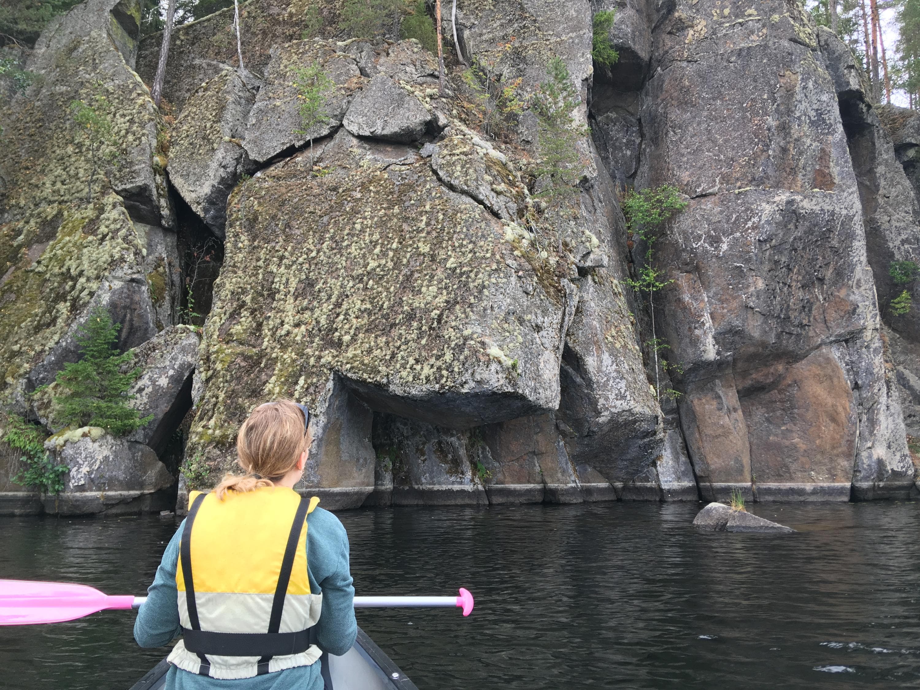 Bild: Maija Mikkola En vandrare paddlar och tittar på klippan.