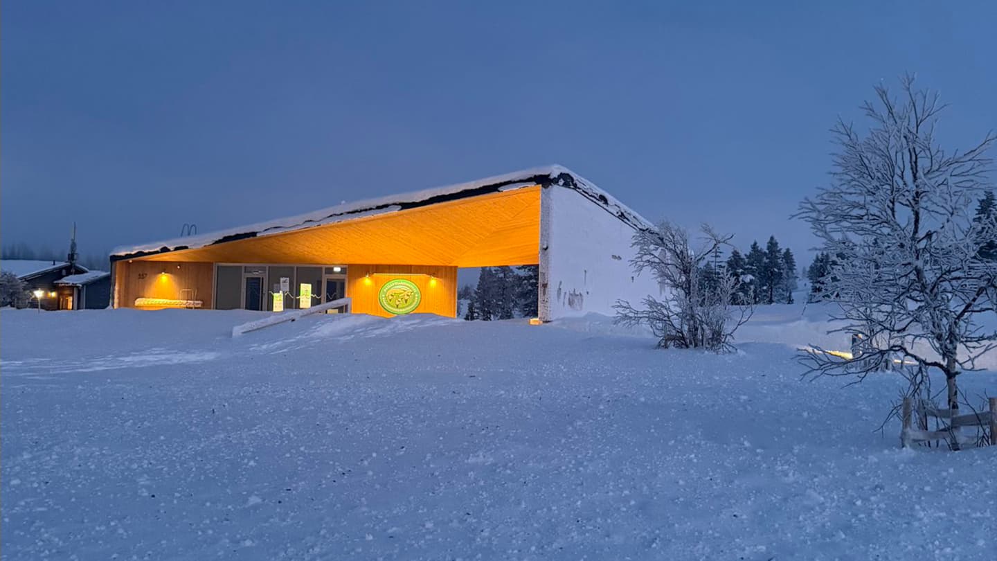 Image: Heta Kylmämaa An illuminated wooden building with a large emblem on the wall.