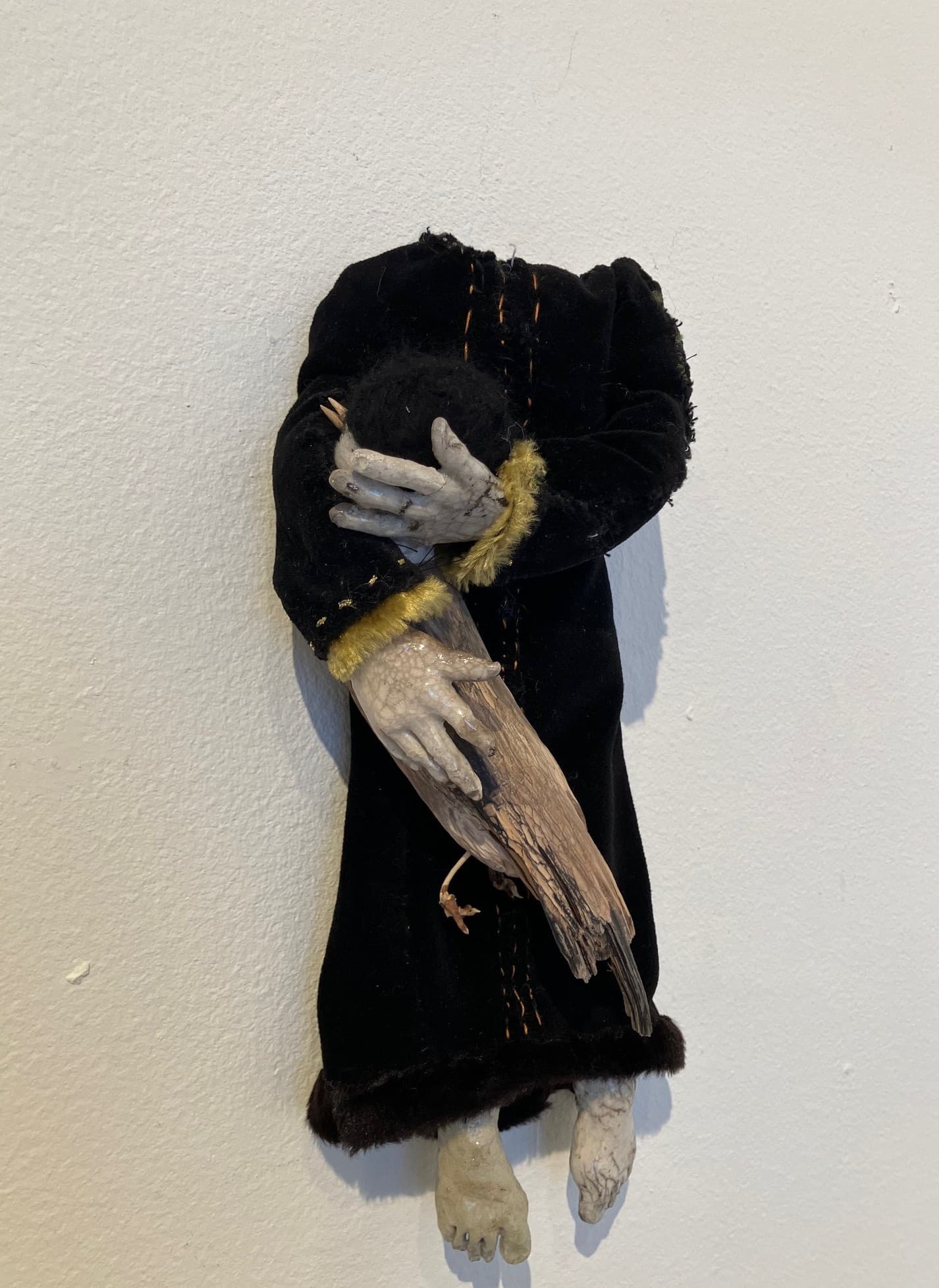 Kuva: Jonna Salonen Puusta ja tekstiilistä koottu reliefi, jossa päätön ihmishahmo kantaa sylissään hömötiaista.