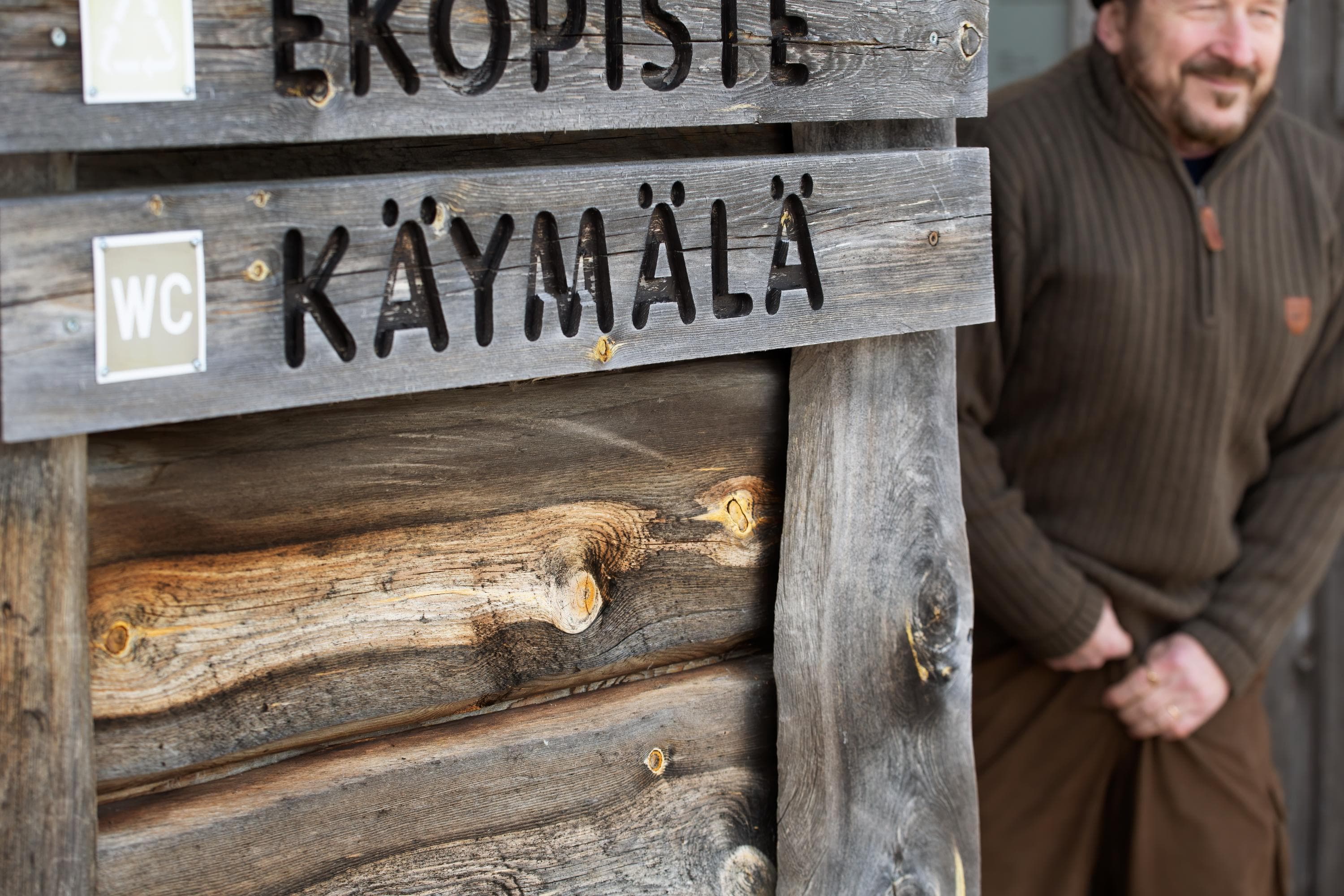 Kuva: Katri Lehtola Retkeilijä on tulossa käymälästä. Seinällä on kyltit "käymälä" ja "ekopiste".