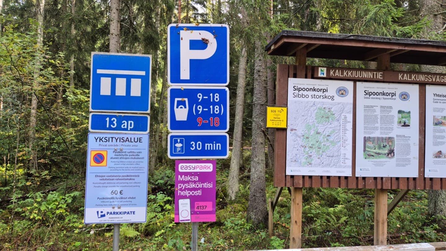 Kuva: Pavel Sateenkoski Metsän laidassa maksullinen pysäköintikyltit sekä osa opastustaulusta.