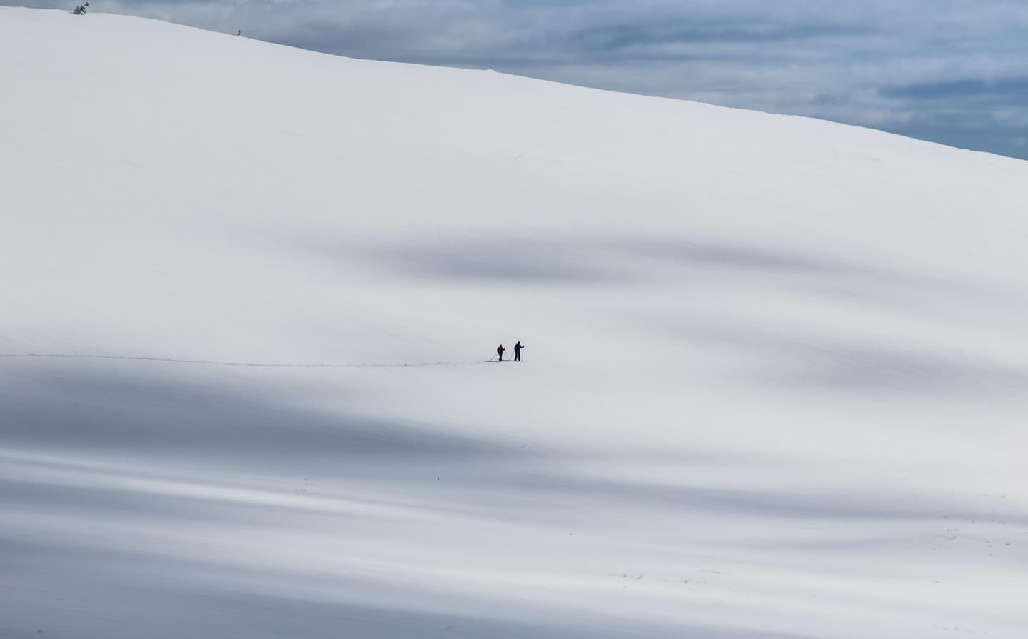 Image: Pertti Turunen Two skiers can be seen in the distance on a sunlit fell slope.