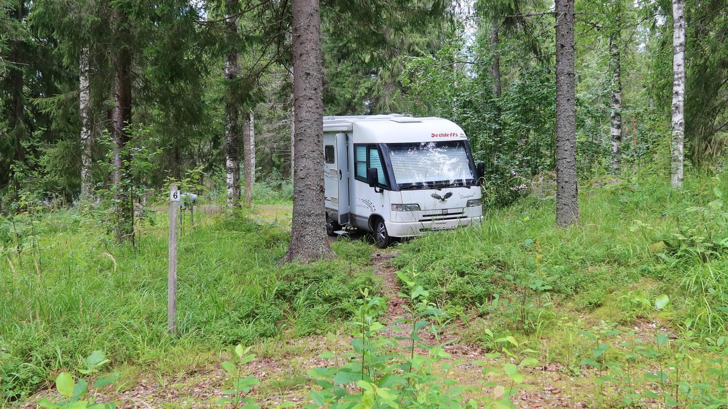 Image: Katja Granskog A motorhome parked in a wooded setting. The number 6 on the post marks the parking space.