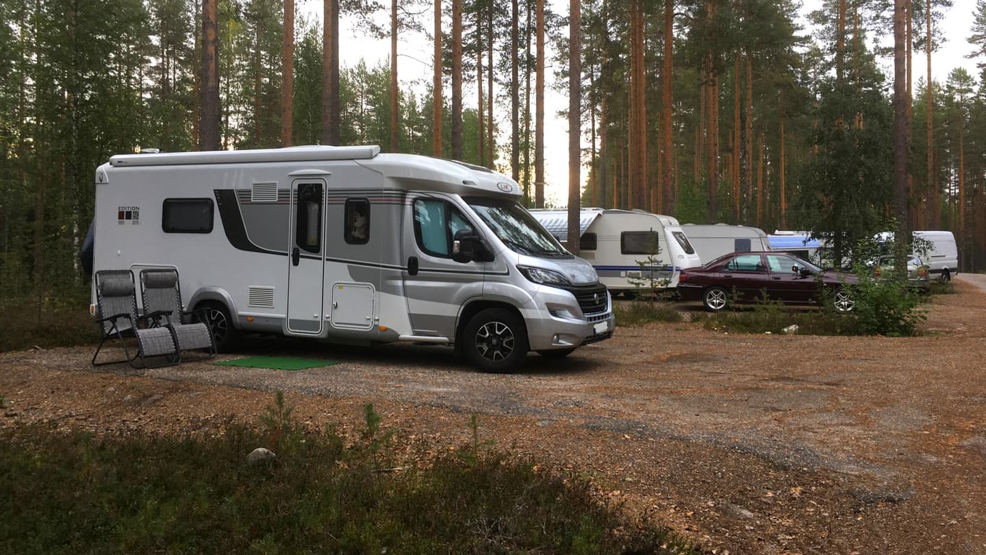 Image: Metsähallitus Motorhomes and car–caravan combinations parked in a designated area at the edge of a forest.