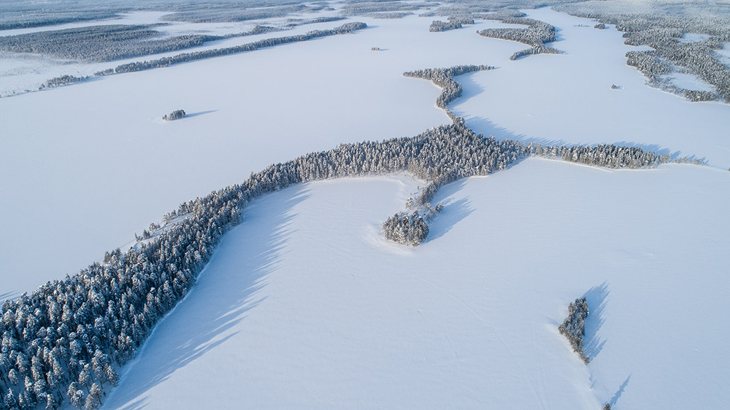 Ilmakuvassa pitkä harju Kalmoniemi ja jäätynyt Tiilikkajärvi.
