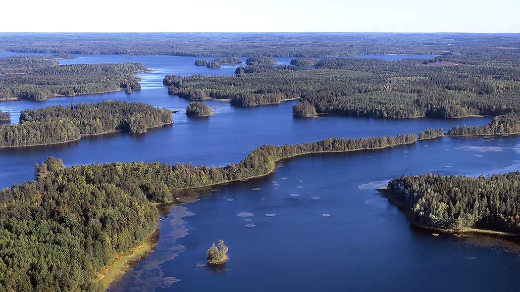 Ilmakuva, jossa näkyy järvi ja puustoisia saaria kesällä.