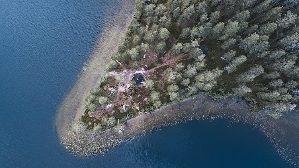 Kylmlauoma strövområdet fotograferat från luften. En koja omgiven av en skog på spetsen av en udde.