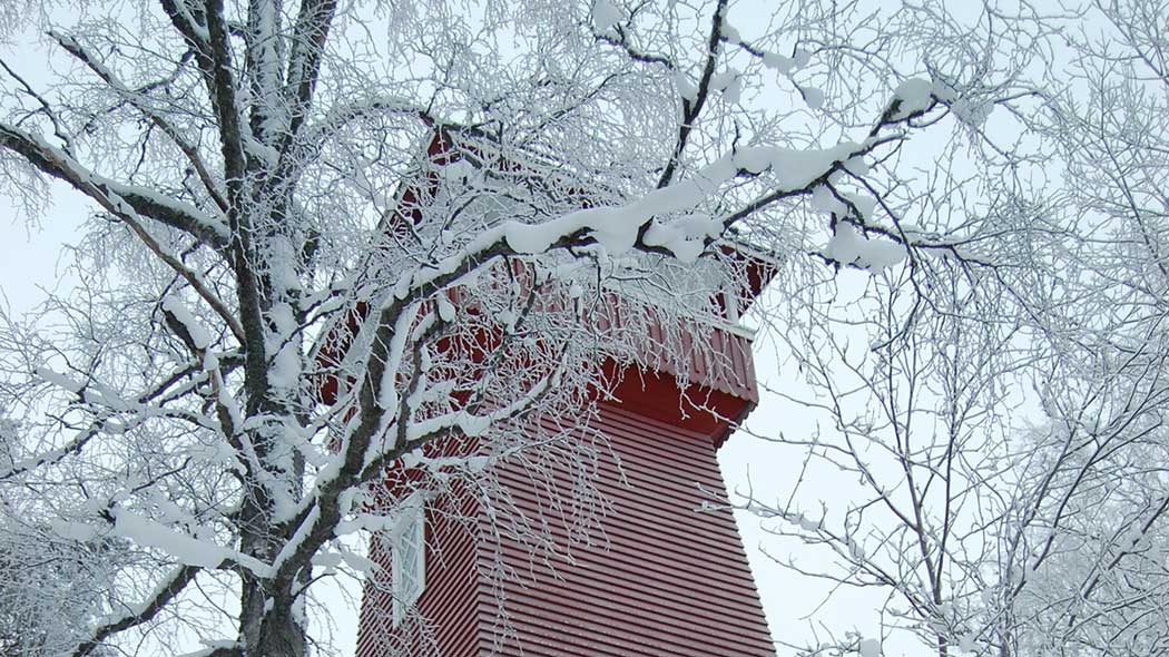 Puinen näkötorni on huurussa. Tornin vierellä kasvavat lehtipuut ovat lumen peitossa.